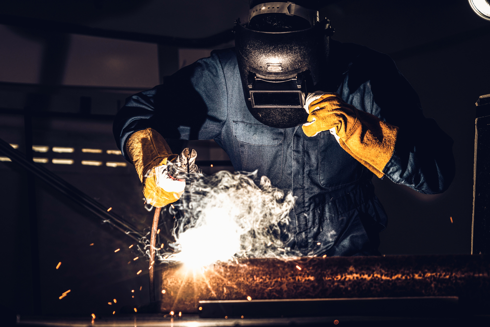 金属焊工使用电弧焊机在工厂焊接钢同时佩戴安全设备手工技能劳动理念的金属制品制造和建筑维修服务